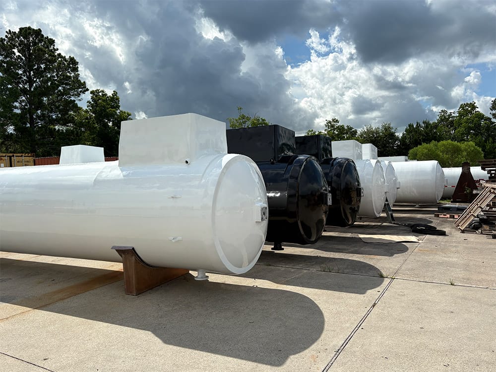 Barrel-only tanks from Poly-Coat Systems staged outdoors without complete trailer chassis.