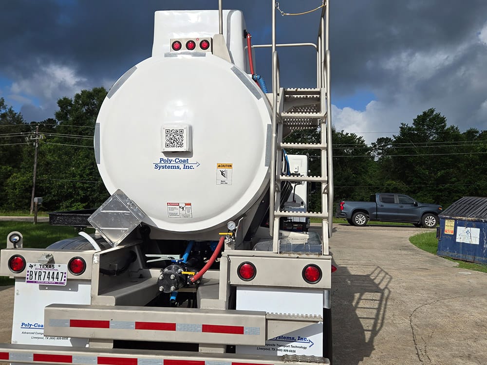 Rear view of a stock tank trailer from Poly-Coat Systems showing the ladder, piping and trailer frame.