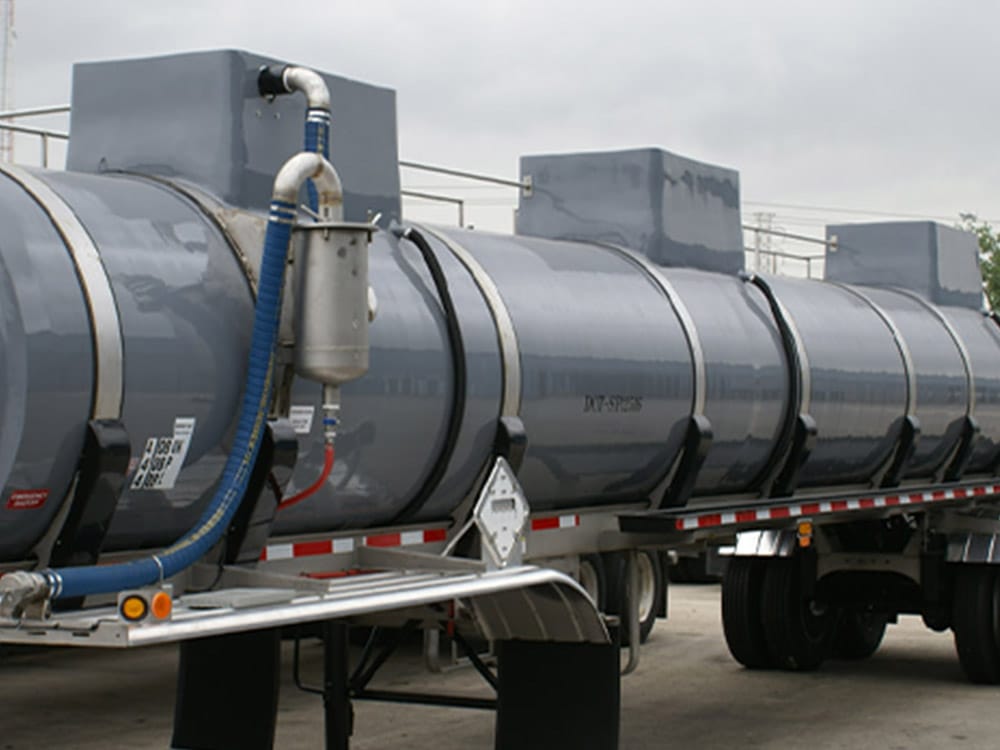 Vacuum tank trailer featured by Poly-Coat Systems with vacuum hose, piping and separator canister visible.
